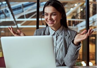 Delighted brunette sitting in front of computer and listening to new information about trading